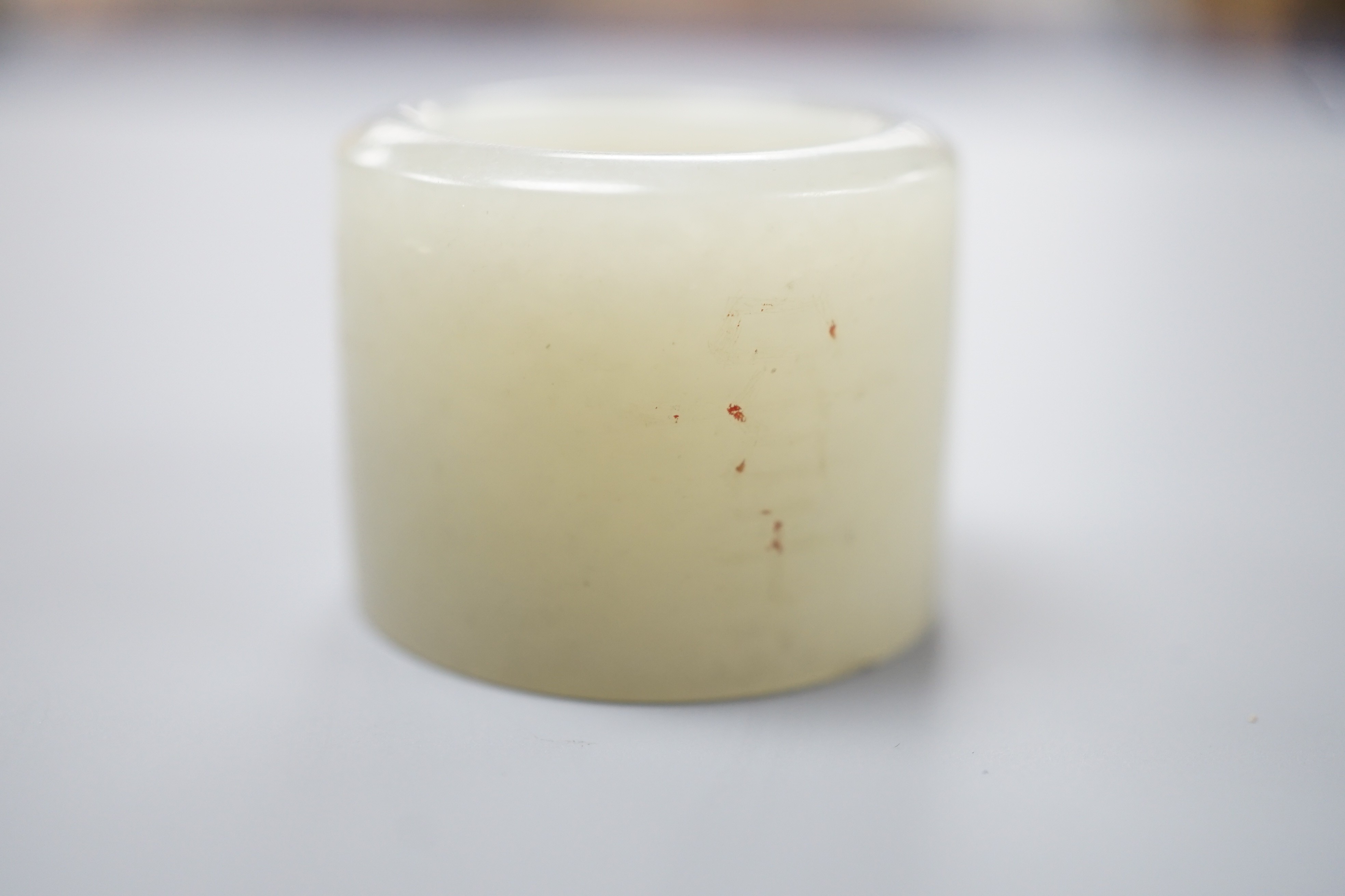 A 19th century Chinese pale celadon jade archer’s thumb ring, inscribed, 3 cm diameter
